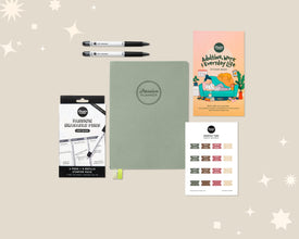 Collection of Passion Planner products including a planner, stickers, and pens on a beige background.