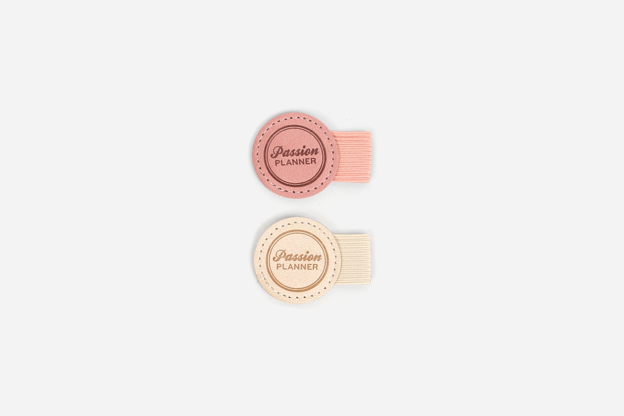 Two round, pink and cream colored pen loops with 'Passion Planner' text on a white background.